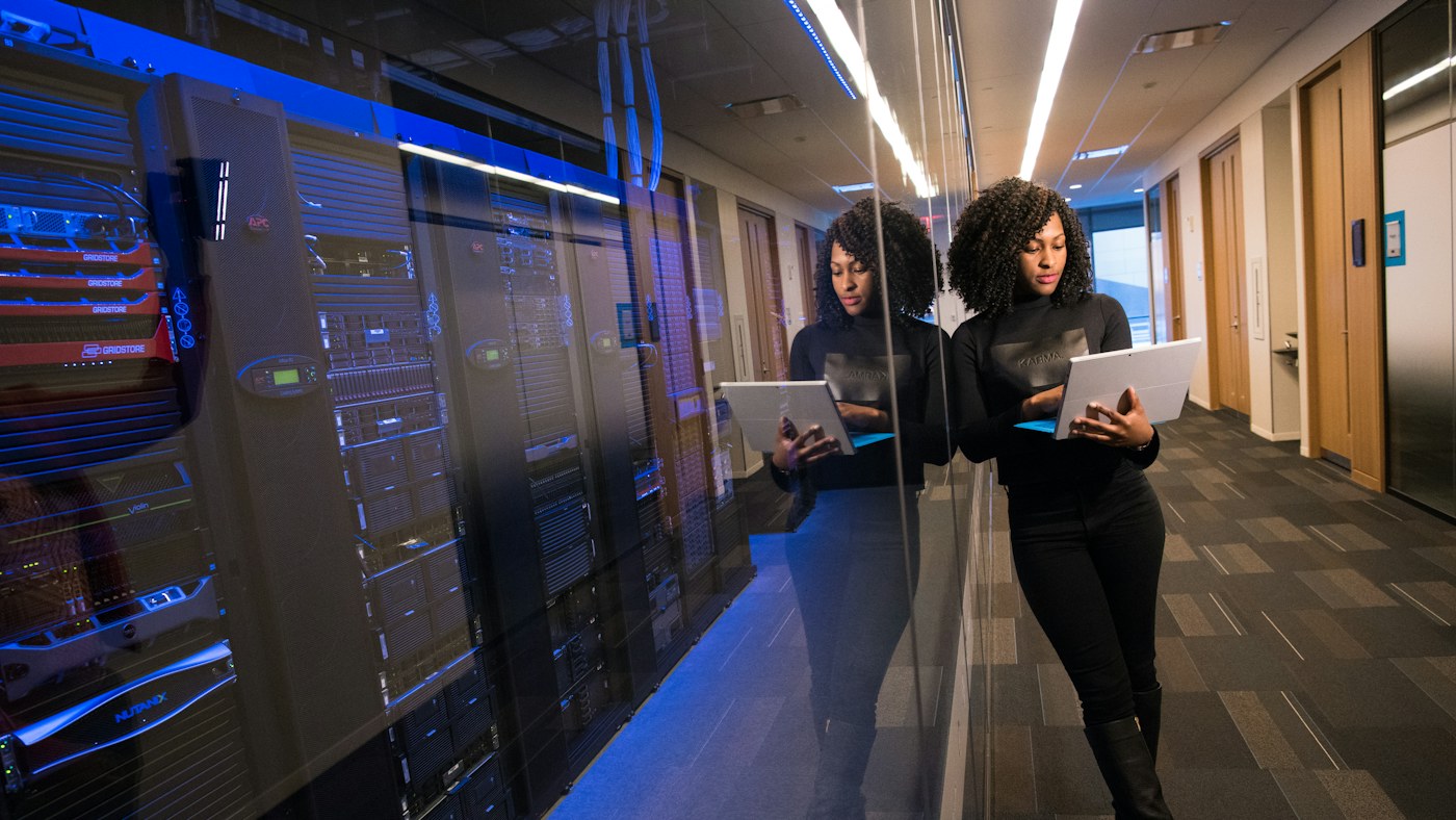 IT professional using a laptop beside server racks