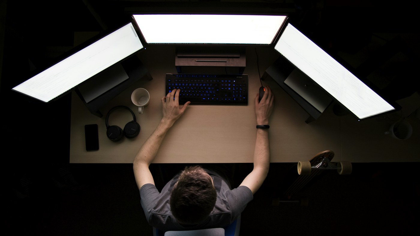 Analyst working at a desk with three monitors
