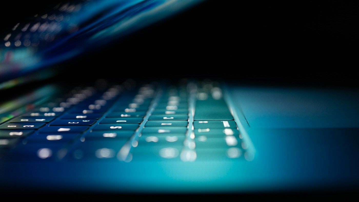 Close-up of a laptop keyboard illuminated in blue